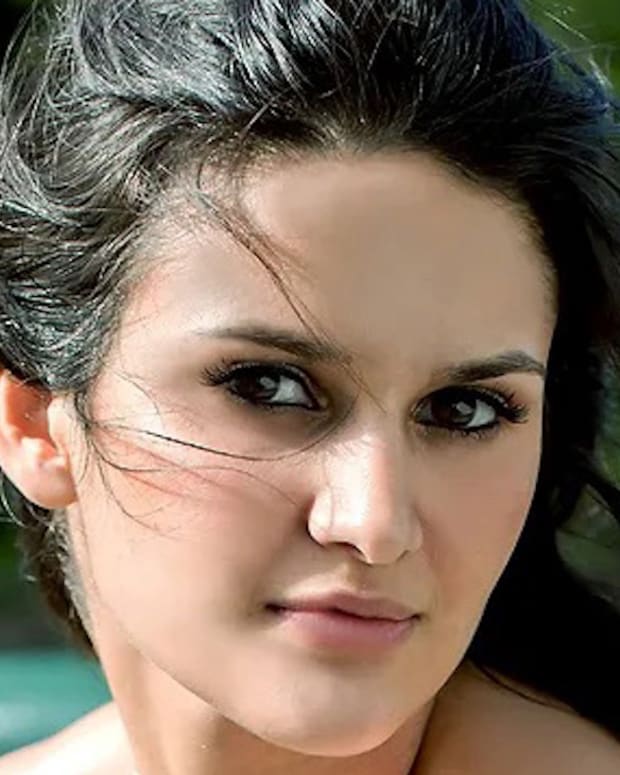 Leryn Franco poses in front of a vibrant blue lake and looks intently at the camera.